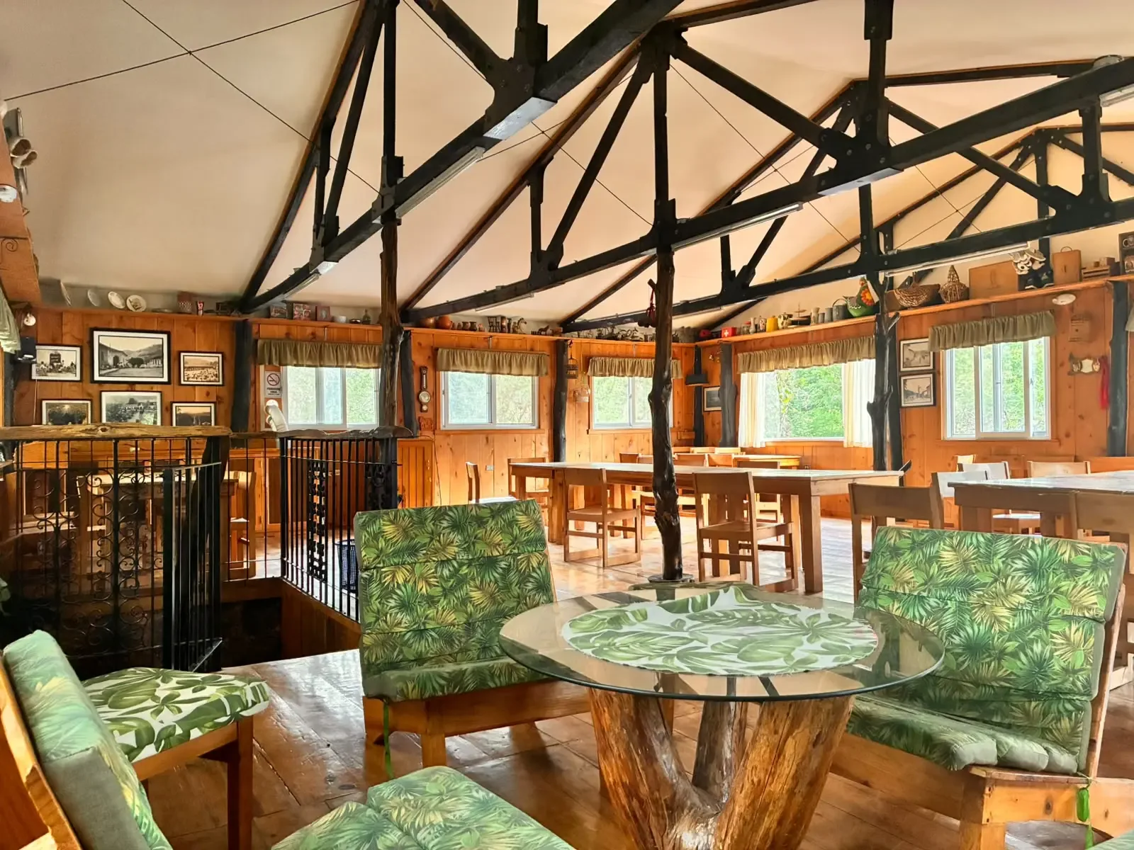 Comedor rústico con mesas largas de madera, vigas y ventanas hacia la naturaleza