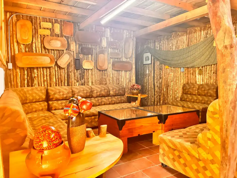 Sala de Aguacatillo con sofás, paredes de madera y objetos tradicionales de la cultura local