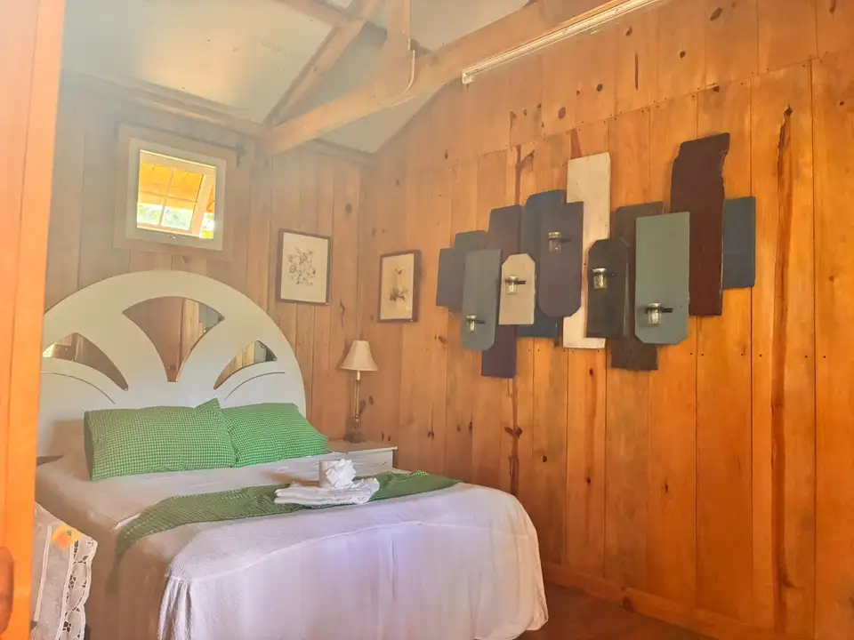 Dormitorio de Platanar con cama doble, textiles verdes y paredes de madera