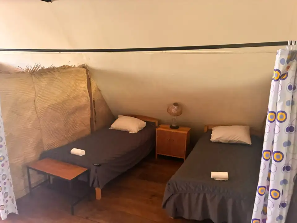 Segundo dormitorio de Aguacatillo con camas individuales, cortinas de colores y suelo de madera